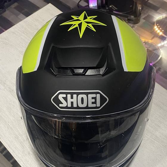 Casco de moto negro mate con vinilo amarillo flúor, blanco y una estrella náutica, visto desde arriba