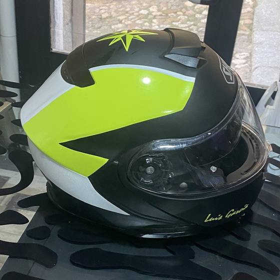 Casco de moto con franjas de vinilo amarillo flúor y blanco, visto de lado