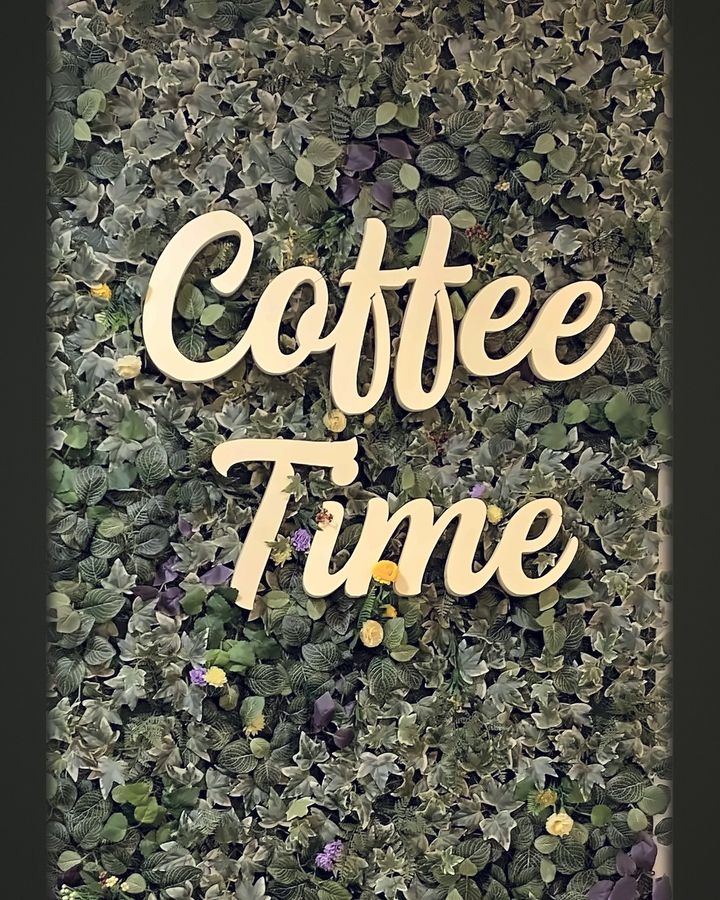 Letras corpóreas Coffee Time sobre muro vegetal